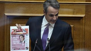 Greece's Prime Minister Kyriakos Mitsotakis holds a copy of a Greek newspaper's front page during his speech at the parliament in Athens, Greece, Aug. 26, 2022. 