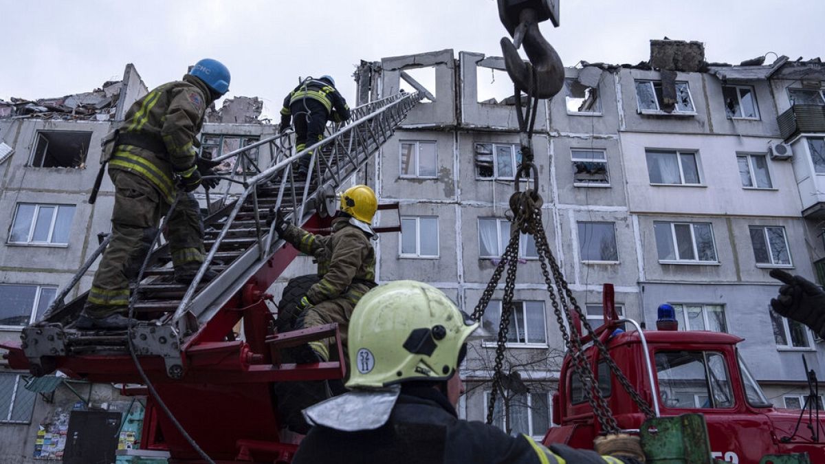Mentőmunkások létrán másznak fel, miközben eltakarítják az orosz rakéta által megsemmisített lakóépület romjait az ukrajnai Pokrovszkban 2023. február 15-én. 