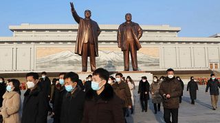 كوريون شماليون أمام تمثالي الزعيمين كيم جونغ إل وكيم إل سونغ