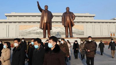 كوريون شماليون أمام تمثالي الزعيمين كيم جونغ إل وكيم إل سونغ