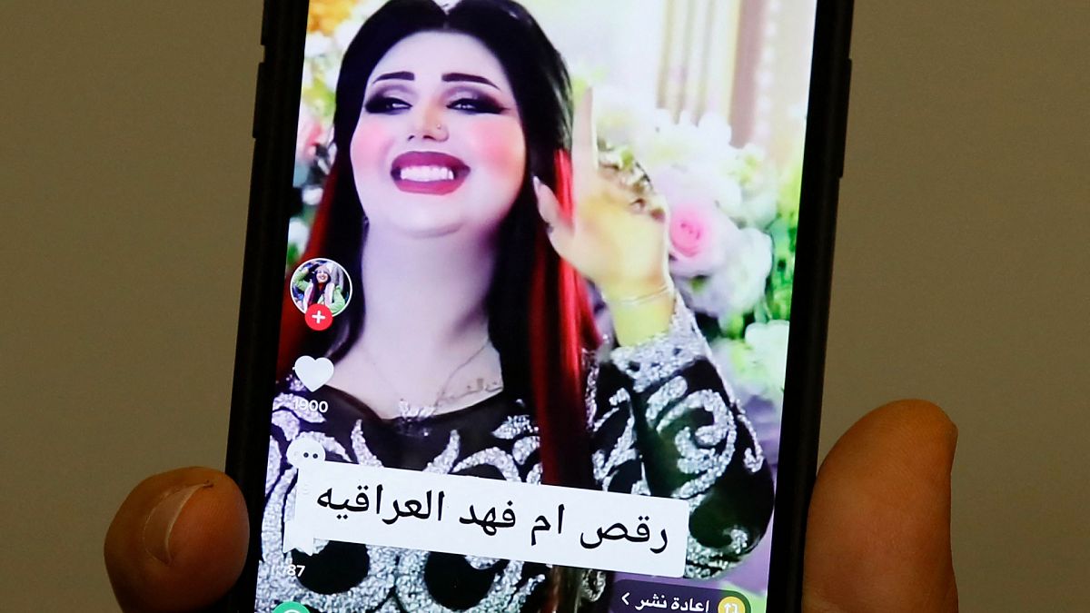 رجل عراقي يحمل هاتفاً وهو يتصفح حساب "أم فهد" التي حكم عليها بالسجن 