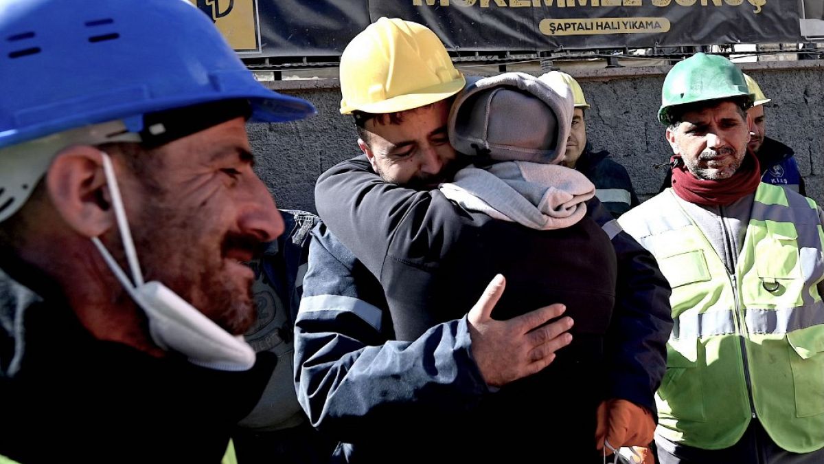   عم الشابة التركية ألينا أولمز (في الوسط) يُعانق عمال الاغاثة الذين أنقذوها بعد 248 ساعة من الزلزال،  كهرمان ماراس- 16 فبراير 2023.