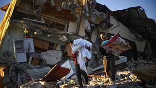 Die wenigen Habseligkeiten, die sie unter den Trümmern finden, bringen diese beiden Männer in der türkischen Erdbebenregion in ihre Übergangsunterbringung.