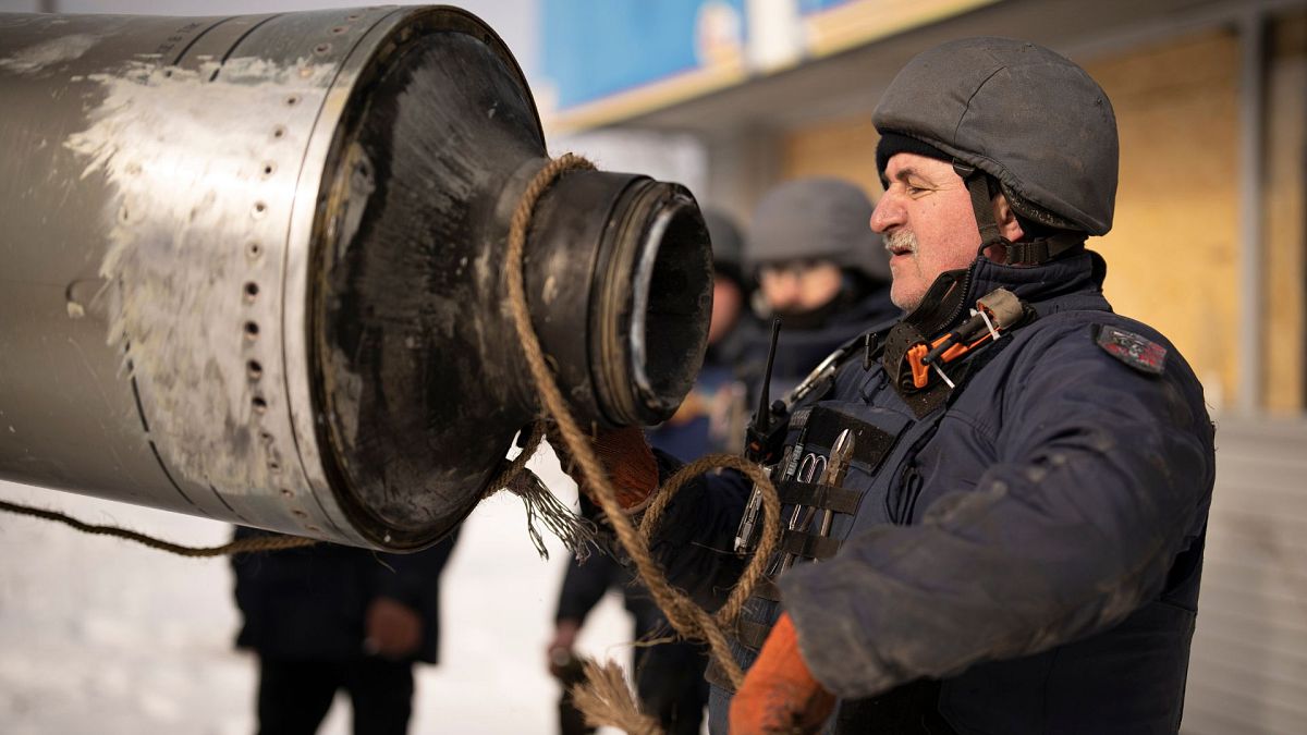 A Ukrainian emergency services employee uses a rope to secure te remains of an S-300 missile fired by Russian forces in Kharkiv, Ukraine