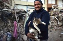 Férfi a macskájával, akit egy összedőlt épületből mentettek ki a dél-törökországi Kahramanmarasban