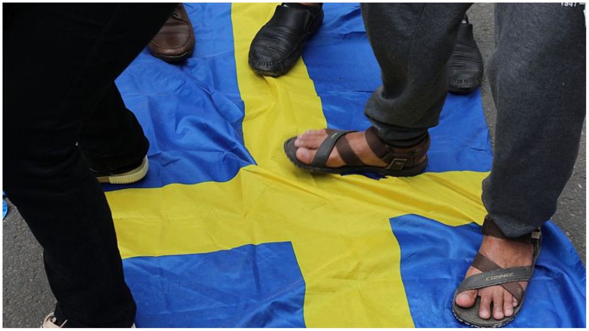  نشطاء يقفون على العلم السويدي خلال تجمع لمتظاهرين خارج السفارة السويدية في جاكرتا في الـ 30 يناير-كانون الأول 2023