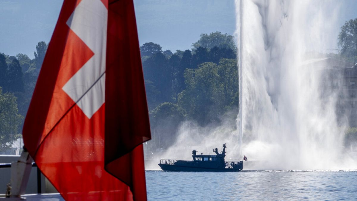 Ένα σκάφος της αστυνομίας περνά δίπλα από μια ελβετική σημαία και ένα σιντριβάνι στη λίμνη της Γενεύης στη Γενεύη, Ελβετία, Τρίτη 15 Ιουνίου 2021. 
