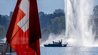 A police boat passes by a Swiss flag and a fountain on the Lake Geneva in Geneva, Switzerland Tuesday, June 15, 2021. 