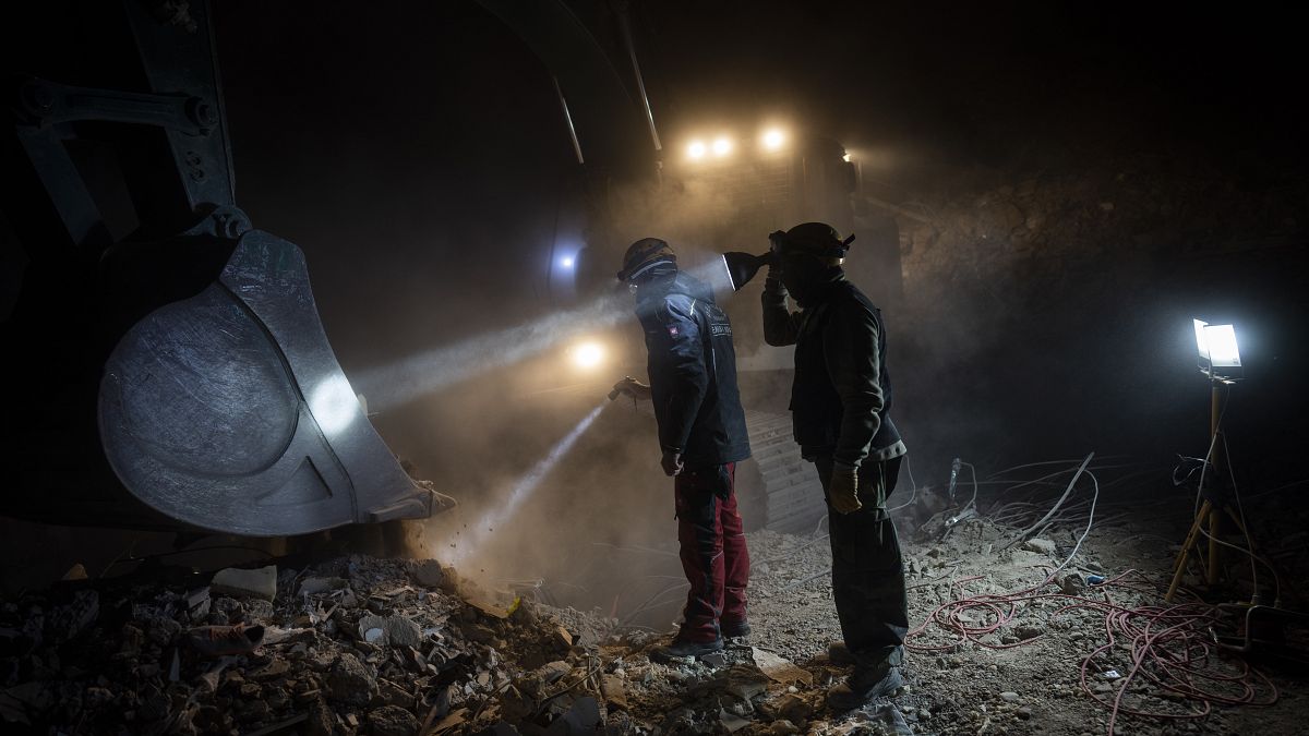 Des membres de l'ONG Deathcare Embalming Team et le turc Kurt-Ar inspectent le godet d'une excavatrice alors qu'ils recherchent des corps après le tremblement de terre