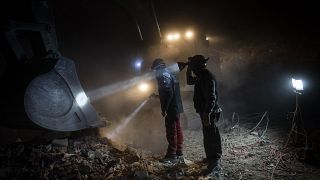 Des membres de l'ONG Deathcare Embalming Team et le turc Kurt-Ar inspectent le godet d'une excavatrice alors qu'ils recherchent des corps après le tremblement de terre
