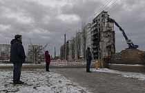 Местные жители смотрят, как разбирают взорванное здание в Бородянке, 13 декабря 2022 года