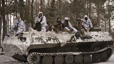 Ukrainian servicemen, ride on top of an armoured transporter 