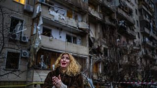Natali Sevriukova is overcome with emotion as she stands outside her destroyed apartment building following a rocket attack in Kyiv, Ukraine, Friday, Feb. 25, 2022