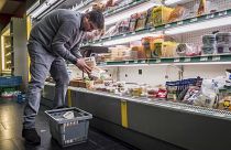 A worker removes expired food in a local supermarket in Brussels.