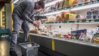 A worker removes expired food in a local supermarket in Brussels.