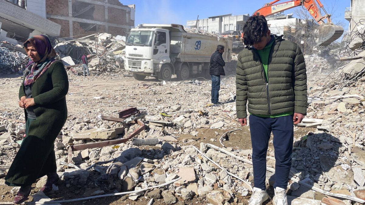 Taha Erdem (r), his mother Zeliha Erdem (l) and father Ali Erdem stand next to the debris from a building where Tahan was trapped after the earthquake in Adiyaman, Turkey.