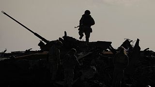 Ukrán katona egy orosz harckocsi roncsain