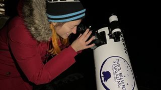 Euronews Travel journalist Hannah Brown looking through a telescope