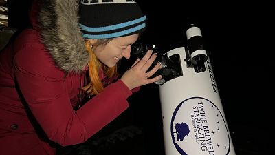 Euronews Travel journalist Hannah Brown looking through a telescope