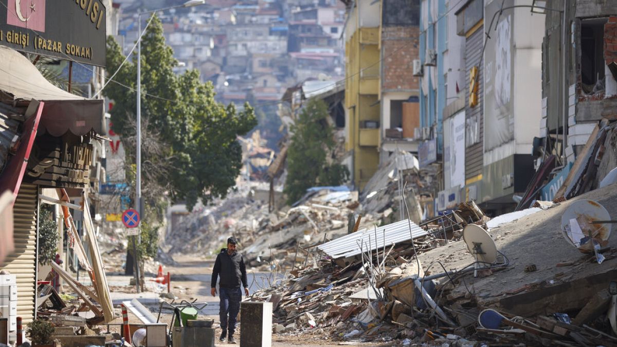 Homem passa por rua destruída pelos sismos em Antakya, Turquia