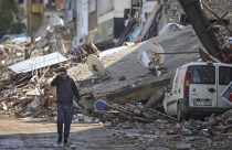 A man walks past debris from destroyed buildings in Antakya, southeastern Turkey, Tuesday, Feb. 21, 2023.