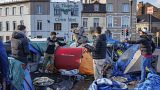 Des hommes organisent leurs affaires dans un camp de tentes de fortune devant le centre d'accueil du Petit Château à Bruxelles, le mardi 17 janvier 2023