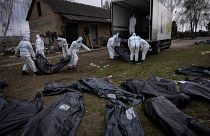 Voluntários recolhem cadávares de civis, mortos em Bucha, para serem levados para uma morgue para investigação