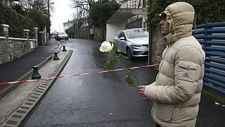 A youth holds a white rose at the entrance of a private Catholic school after a teacher of Spanish has been stabbed to death by a high school student, Wednesday, Feb. 22, 2023