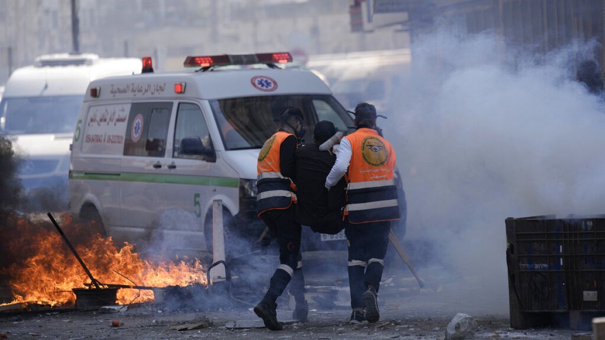 Medics run through tear gas as they evacuate a wounded Palestinian during clashes with Israeli forces in the West Bank city of Nablus, Wednesday, Feb. 22, 2023. 