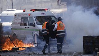 Medics run through tear gas as they evacuate a wounded Palestinian during clashes with Israeli forces in the West Bank city of Nablus, Wednesday, Feb. 22, 2023. 