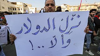  رجل يحمل لافتة كتب عليها بالعربية "نزل ​ الدولار والا ..!" خلال احتجاج على تخفيض قيمة الدينار العراقي مقابل الدولار خارج مقر البنك المركزي العراقي بغداد، 25 يناير 2023