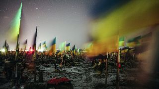 2023. február 23-án közreadott, hosszú expozíciós idővel készített kép ukrán zászlókról a harkivi katonai temetőben február 22-én éjjel.