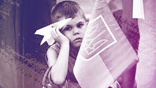 A boy holds a paper plane during a protest by Ukrainian refugees in Bucharest, July 2022