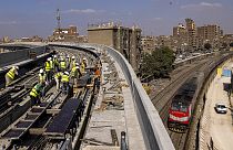 عمال بناء يعملون على مسارات موضوعة حديثا للخط الثالث لمترو القاهرة، في محطة إمبابة الجديدة بالجيزة، 18 أكتوبر 2022 .