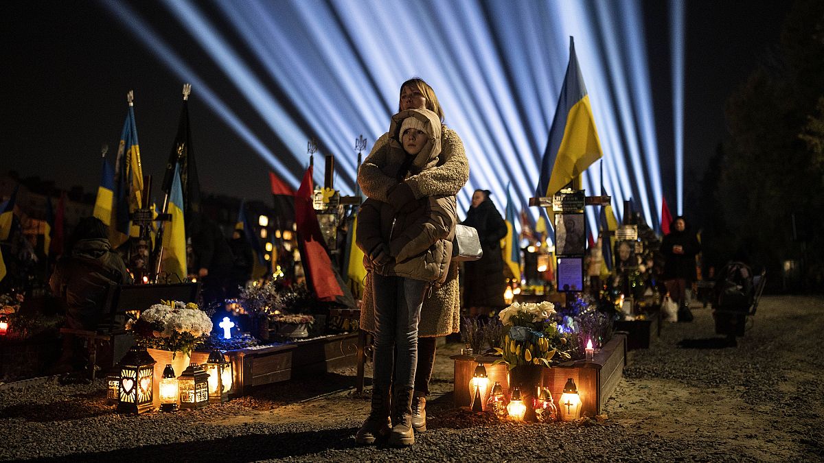 والدة أوكرانية وابنتها تصليان لراحة نفس الجنود الأوكرانيين الذين سقطوا في الحرب في لفيف 