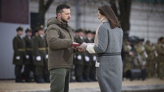 Der ukrainische Präsident Wolodymyr Selenskyj überreicht der Angehörigen eines gefallenen Soldaten einen Orden.