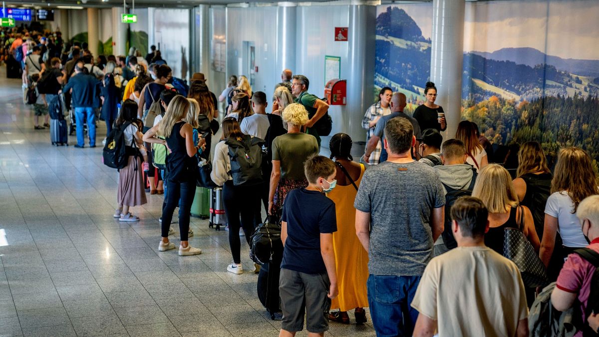People stand in a long queue in front of the security check at the international airport in Frankfurt, Germany.