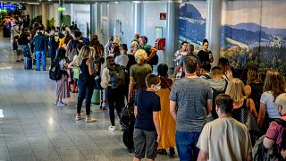 People stand in a long queue in front of the security check at the international airport in Frankfurt, Germany.