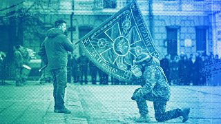 Ukrainian President Volodymyr Zelenskyy holds the flag of a military unit as an officer kisses it in Kyiv, 24 February 2023
