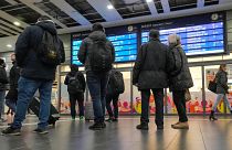 Reisende betrachten einen Informationsbildschirm am Hauptbahnhof in Essen, Deutschland, als die meisten Züge am Donnerstag, 16. November 2023, ausfielen.