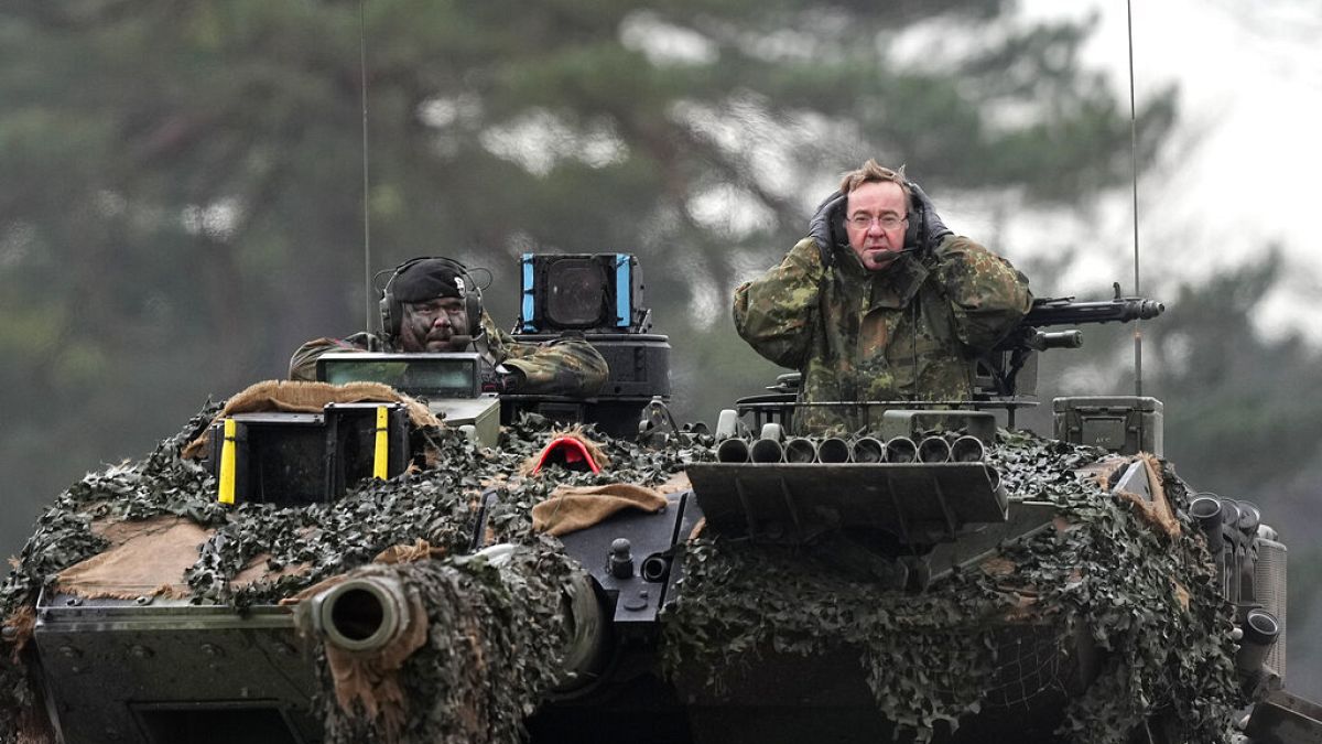 German Defense Minister Boris Pistorius, right, sits on a Leopard 2 tank