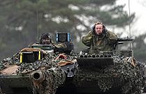 German Defense Minister Boris Pistorius, right, sits on a Leopard 2 tank