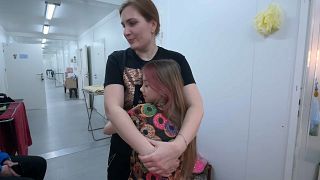 Tatjana Matjusenko egy kislányt ölel magához a bucsai ideiglenes otthonban.