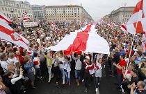 Demonstrators carry a huge historical flag of Belarus as thousands gather for a protest at the Independence square in Minsk, Belarus.