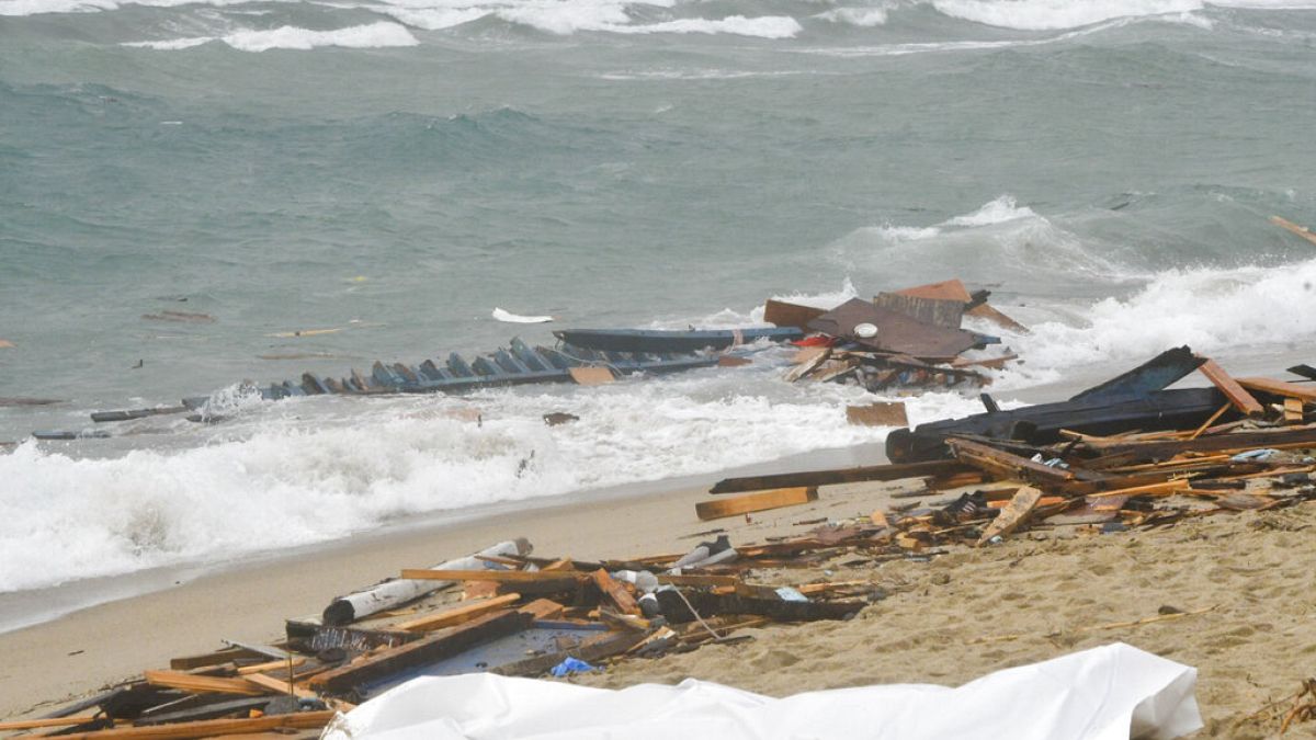 Un cuerpo y los restos de una embarcación volcada en una playa cerca de Cutro, en el sur de Italia, el domingo 26 de febrero de 2023.