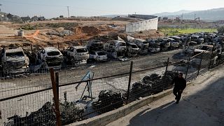 فلسطيني بالقرب من سيارات أحرقها مستوطنون في الضفة الغربية الأحد 