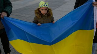 Ukrainian young boy stands close to Ukraine flag while taking part in a protest marking one year since Russia's invasion of Ukraine, in Pamplona, northern Spain, 24 Feb. 