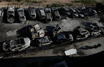 Palestinians walk past burned cars in the town of Hawara, near the West Bank city of Nablus, Monday, Feb. 27, 2023.