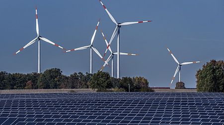 Wind turbines turn behind a solar farm in Rapshagen, Germany, Oct. 28, 2021.