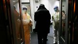 Health Officials in hazmat suits wait at the gate to check body temperatures of passengers arriving from the city of Wuhan, at the airport in Beijing, China, Jan. 22, 2020.